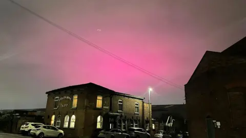 Dave T Callacher Pink skies over a pub in Gorton shows the glow of stadium lights at the Etihad.