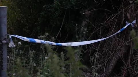 John Fairhall/BBC Police cordon and car in the Newmill Lane area of Brantham, Suffolk.