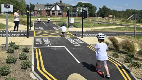 Leeds City Council A bike track with real road signs and traffic lights at a historic estate. Children ride on the park.