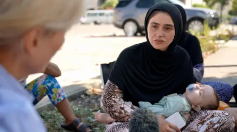 Goktay Koraltan/BBC correspondent Orla Guerin (left) speaks to Madina Mustafa Ali, who is holding her seven-month-old baby Amir