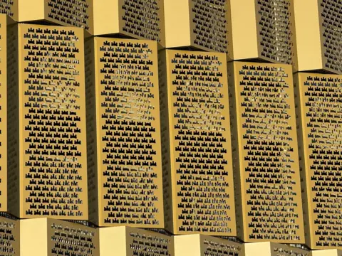 Gold-coloured grills on the side of a multi-storey car park. The panels contain multiple holes which are cut in the shape of a castle.