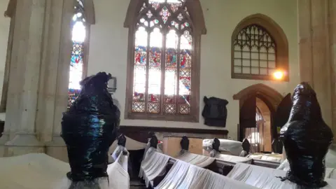 Interior of churched with pews covered in sheets and architectural features wrapped in protective plastic