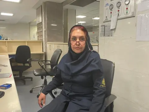 A female nurse sitting at a desk in Tehran