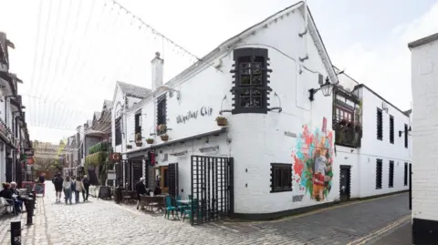 Street view of a cobbled lane with white buildings in the west end of Glasgow