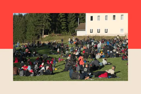 Anadolu via Getty Refugees rest on a field in Wegscheid, Germany after crossing the Austrian - German border