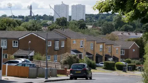 A picture of a black car driving on a residential street in Birmingham.