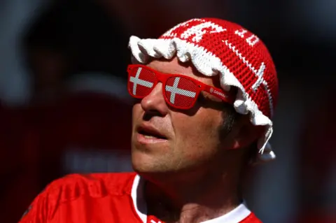 Reuters A man wears a crochet hat and sunglasses in the colours of the Danish flag