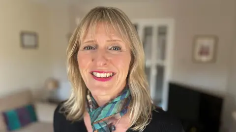 Elaine Davis-Kimble wearing a black top and a patterned scarf against a blurred background