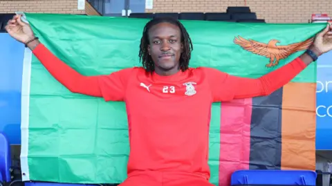 Inverness Caley Jags striker holding Zambian flag.