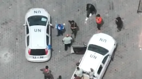 Men the IDF says are armed stand by two UN-marked cars