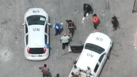 IDF via Reuters Men the IDF says are armed stand by two UN-marked cars