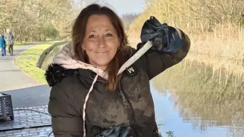 Gill Shilvock Gill Shilvock holding a knife that she has pulled out of a canal, with the waterway in the background