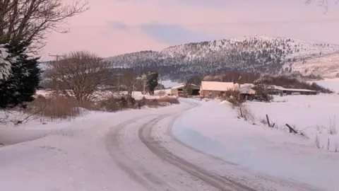 Fubar News A snowy rural road with hills and forests in the background