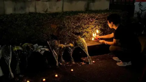 Reuters A woman lights candles near floral tributes placed outside a sports centre where a deadly hit-and-run attack took place, in Zhuhai