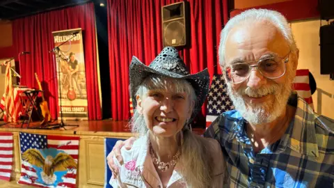 A couple wearing country music-themed clothing 