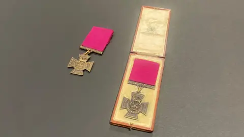 Two Victoria Crosses laid out, the one on the right is in a box.