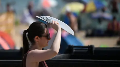 A woman uses a fan to keep cool as the temperature rises in Bournemouth