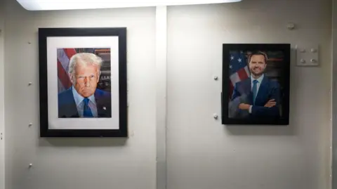 BBC/Natalie Thomas The official portraits of the new US President Donald Trump and Vice-President JD Vance hanging in the living quaters on Carl Vinson