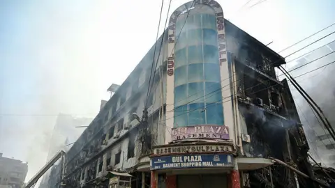 AFP via Getty Images Fire fighters and rescue workers perform a cooling operation amid the debris after a massive fire at a shopping mall in Karachi on January 19, 2026