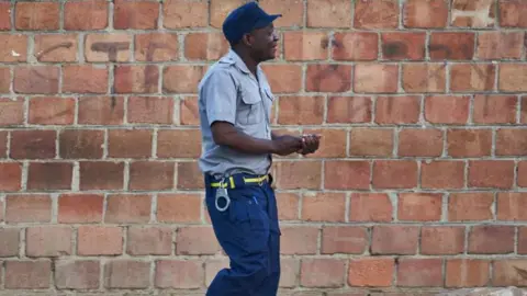 AFP A Zimbabwean police officer walks towards a polling station during Zimbabwe's presidential and legislative elections in Bulawayo on August 23, 2023. Zimbabweans on August 23, 2023