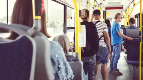 People sitting and standing inside a single-decker bus
