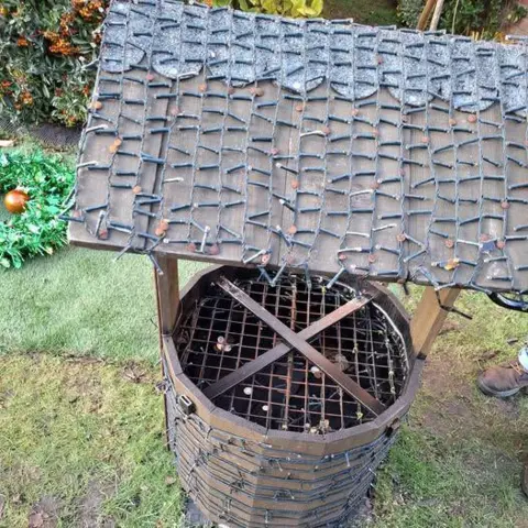 Norfolk Constabulary A small water well with a metal wire grill on top, with a shelter over the top decorated with fairy lights.