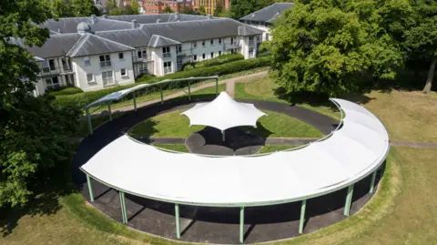 An aerial view of a large white circular canopy in a park