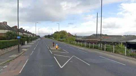 The A630 Fitzwilliam Road in Rotherham. Residential homes run along the road on the left while a garage is on the right. 