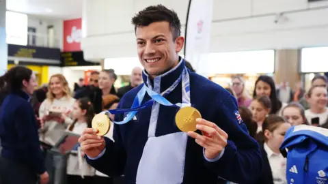 PA Media Great Britain's Matt Weston holding his two gold medals during the Team GB Homecoming, Gatwick Airport.