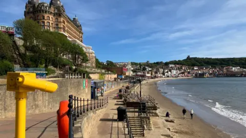 Scarborough seafront with the sea to the right of the image and the sand and the Grand Hotel to the left