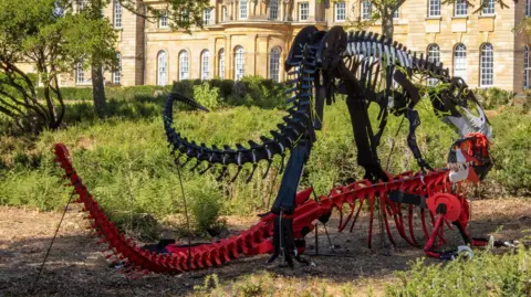 Blenheim Palace A black Megalosaurus sculpture stands over a red one.