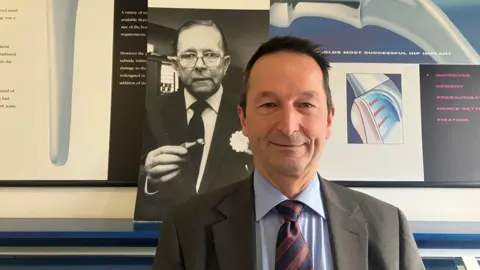 The surgeon Bodo Purbach - in front of a photo of Professor Sir John Charnley.