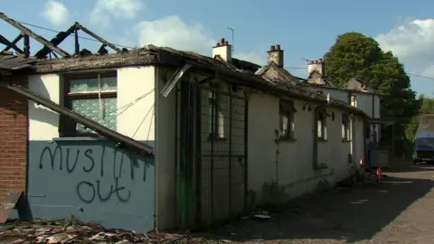 Fire damaged exterior of a bar with "muslims out" spray painted on 