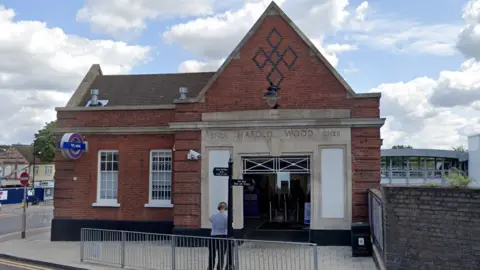 Google Maps Google Street View image of the exterior of Harold Wood Station. It is a small red-bricked building with a purple Elizabeth Line roundel on the outside.