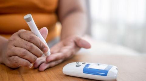 woman with blood sugar meter pricking index finger