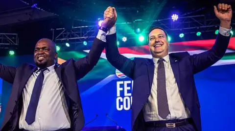 Getty Images Geordin Hill-Lewis is seen holding Solly Msimanga's hand as they celebrate their election