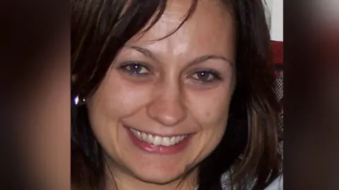 A closeup of Marriclare Bradshaw who has brown hair and brown eyes. She is smiling into the camera.