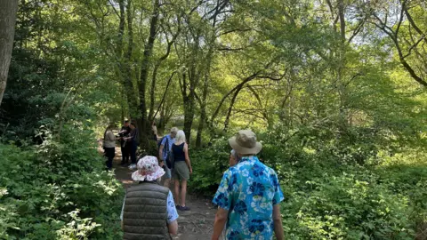 BBC An image of people walking along a path in Burleigh Wood, Loughborough.