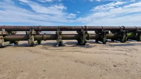 Karen Brotherton A big pipe stretching out across the beach  