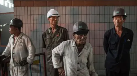 In a photo taken on July 22, 2017 workers watch as molten steel is transfered from a furnace during production at the Chollima Steel Complex, south-west of Pyongyang. 