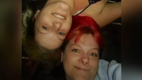 Chloe Callaghan Bethan Callaghan (left) poses for a selfie led down next to her mum, Gaynor, who has red hair and green eyes. Bethan has brown eyes and blonde hair. They both look at the camera. One is facing the right way around and the other is upside-down.