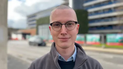 Joseff Reed who has short hair and glasses standing in front of the energy hub