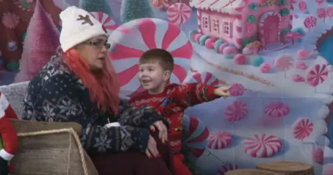 A child smiles as he points out something at the play centre