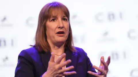 PA Media Chancellor Rachel Reeves gestures with her hands as she speaks at an event.