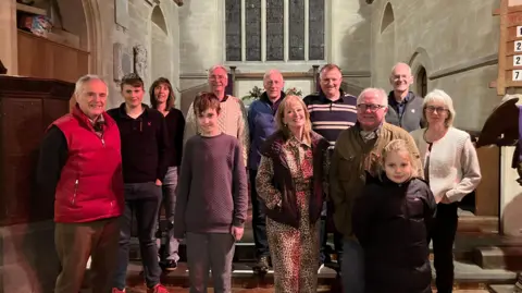 A group of people stood within a church smiling at the camera