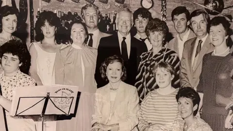 Western Daily Press A black and white photo of the group of musicians which performed form Jimmy Carter in Y Talbot Hotel, Tregaron. Included in this photo are Mr and Mrs Carter, their daughter Amy, Eirioes Ayres and the harpist Rhian Davies