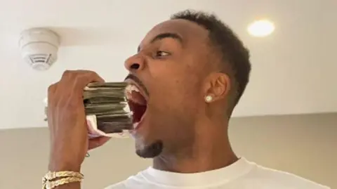 Nottinghamshire Police James poses with a large pile of banknotes next to his open mouth