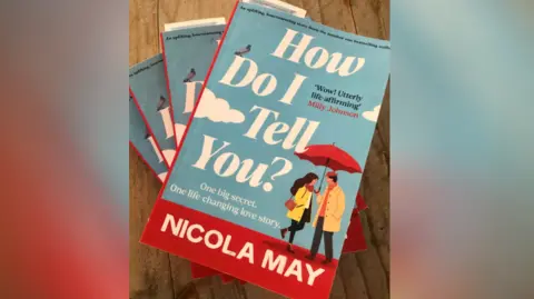 Nicola May Nicola May book which shows an animated man and women under a red umbrella 