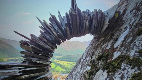 Flat slates piled on top of each other in a curve against a rock face