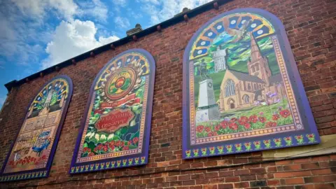 Three arched window-style murals with colourful artwork.